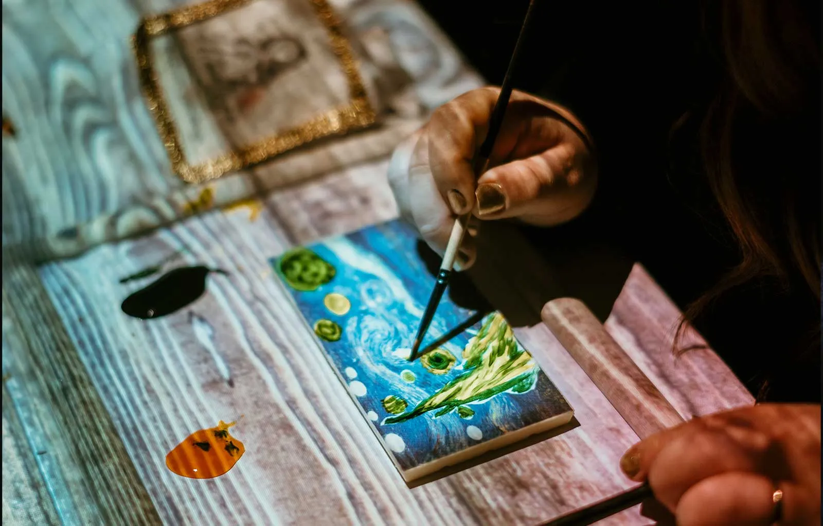 Visitantes pintan La noche estrellada en una mesa luminosa