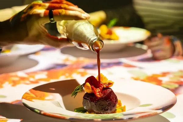Un plato se termina en la mesa con una salsa brillante