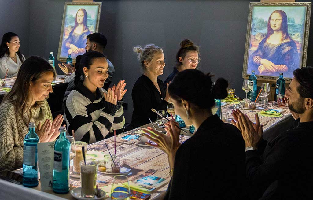 Visitantes aplauden entre dos imágenes de la Mona Lisa durante el espectáculo